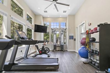 a gym with a treadmill and weights and a tv at Ascent Apartments, Cottonwood Heights